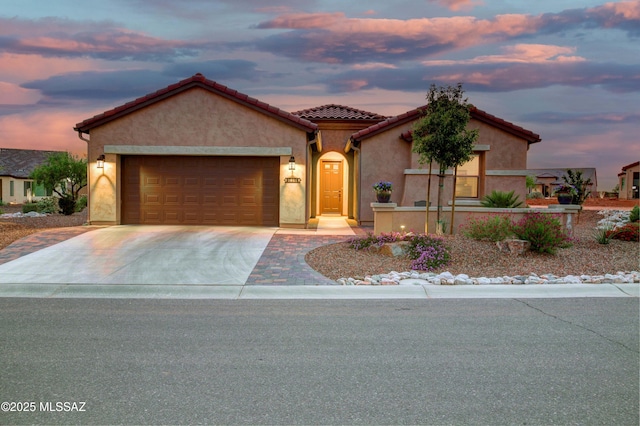 view of front of house with a garage, a tile roof, driveway, and stucco siding