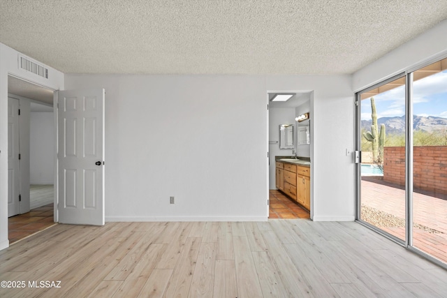 empty room with light hardwood / wood-style floors and a textured ceiling