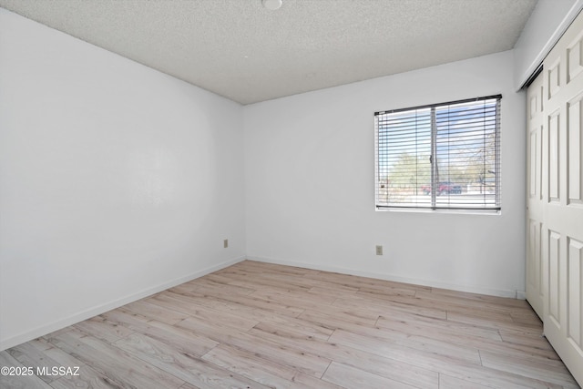 unfurnished room with a textured ceiling and light wood-type flooring