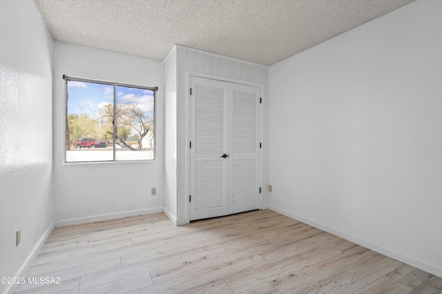 unfurnished bedroom with a closet, a textured ceiling, and light wood-type flooring