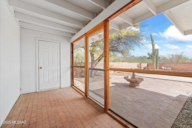 unfurnished sunroom featuring beamed ceiling