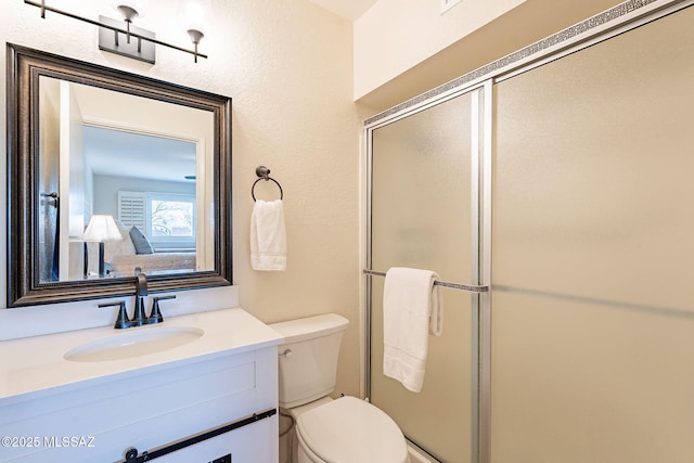 bathroom with vanity, toilet, and a shower with door