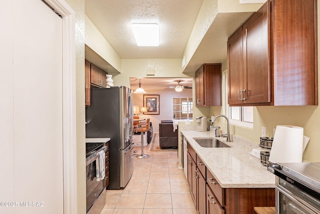 kitchen with pendant lighting, sink, light tile patterned floors, appliances with stainless steel finishes, and a textured ceiling