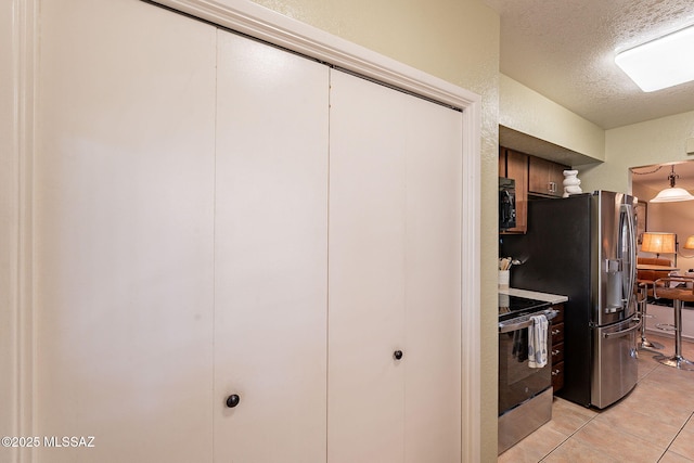 kitchen featuring stainless steel appliances, light tile patterned flooring, and a textured ceiling