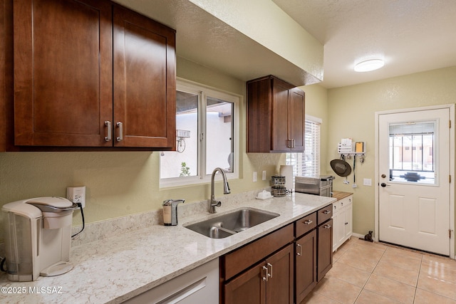 kitchen featuring plenty of natural light, sink, light tile patterned floors, and light stone counters