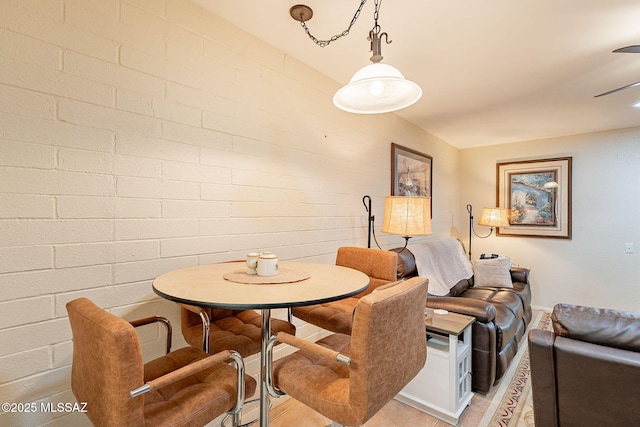 dining space featuring brick wall and light tile patterned floors