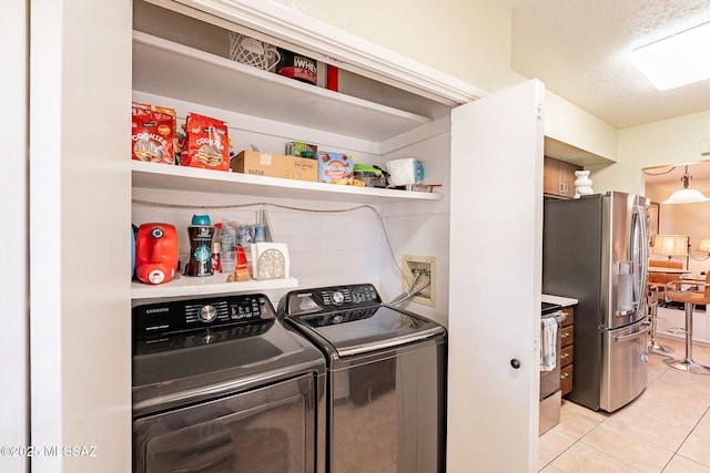 laundry area with light tile patterned flooring, separate washer and dryer, and a textured ceiling