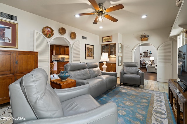 living area featuring arched walkways, visible vents, recessed lighting, and a ceiling fan