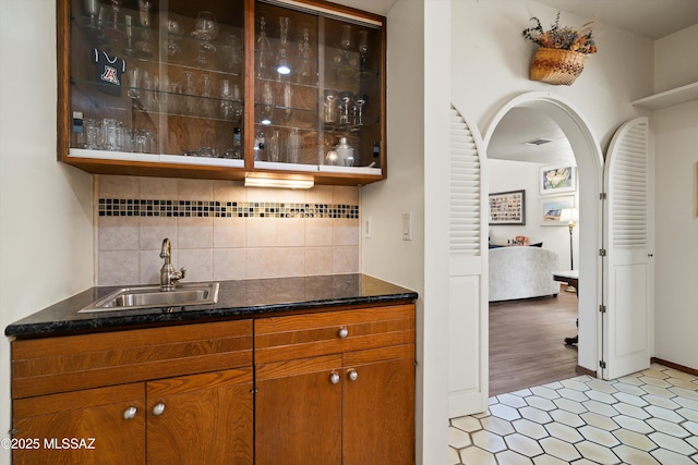 bar with visible vents, wet bar, arched walkways, a sink, and backsplash