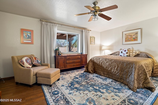 bedroom with ceiling fan, wood finished floors, and a textured ceiling