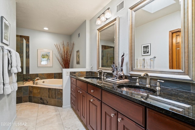 full bath featuring a bath, visible vents, a skylight, and a sink