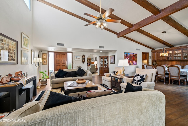 living area featuring arched walkways, visible vents, dark wood finished floors, and beam ceiling