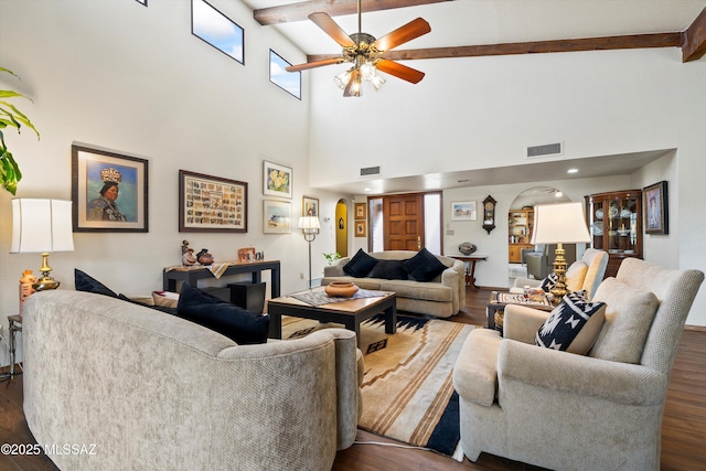 living room featuring beamed ceiling, arched walkways, visible vents, and dark wood finished floors