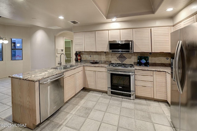 kitchen featuring stainless steel appliances, a peninsula, a sink, visible vents, and backsplash