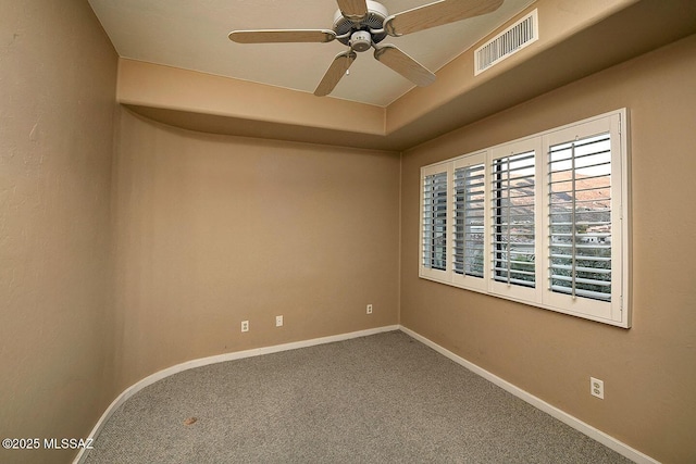 carpeted empty room with baseboards, visible vents, and a ceiling fan