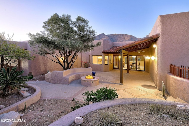 back of property featuring a fire pit, a patio area, fence, and stucco siding