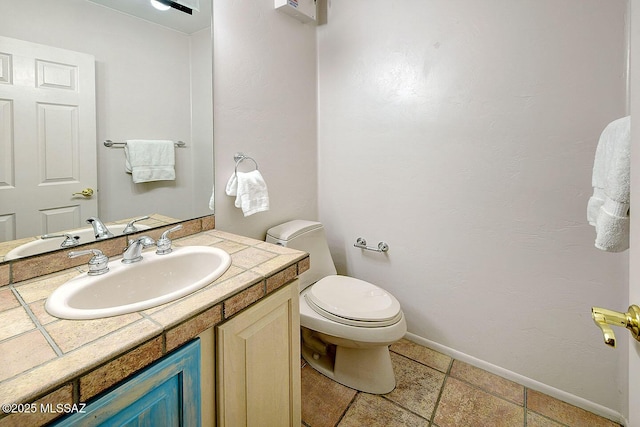 half bathroom featuring toilet, vanity, and baseboards