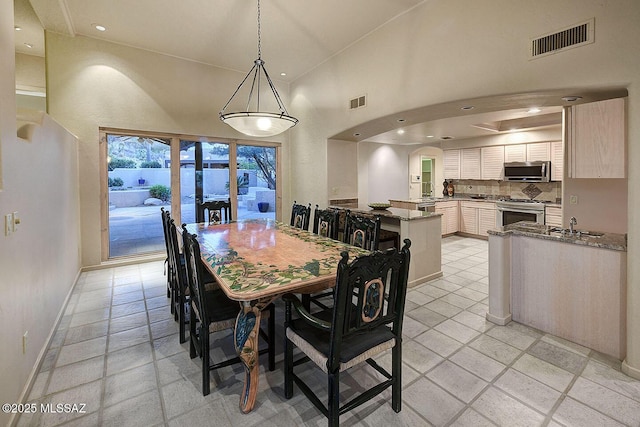 dining space with baseboards, visible vents, arched walkways, a high ceiling, and recessed lighting