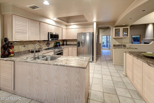 kitchen with visible vents, decorative backsplash, arched walkways, appliances with stainless steel finishes, and a sink