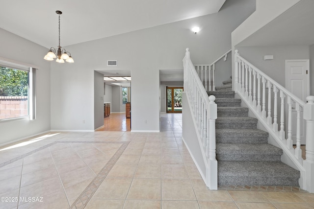 stairs with tile patterned flooring, high vaulted ceiling, and a chandelier