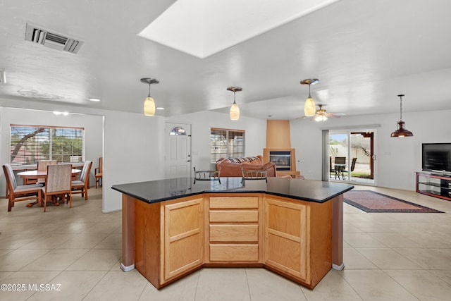 kitchen with a center island with sink, plenty of natural light, light tile patterned floors, and decorative light fixtures