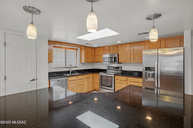 kitchen featuring hanging light fixtures, a skylight, stainless steel appliances, and sink