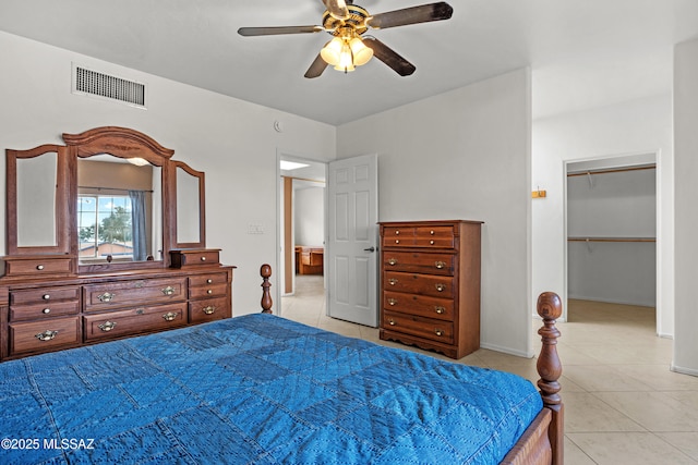 bedroom with a walk in closet, ceiling fan, and light tile patterned flooring