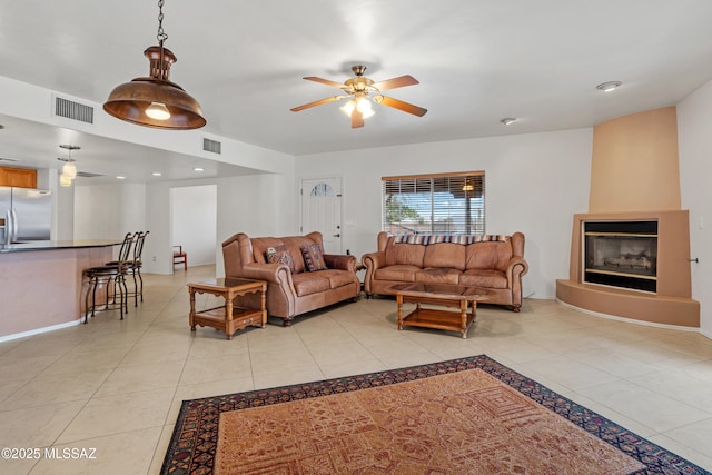 tiled living room with a large fireplace and ceiling fan