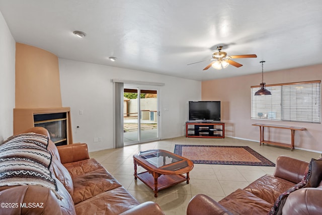 living room featuring a large fireplace, light tile patterned floors, and ceiling fan