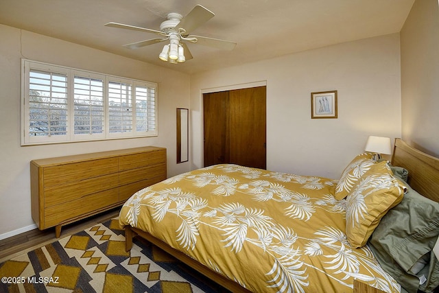 bedroom featuring a closet, wood finished floors, a ceiling fan, and baseboards