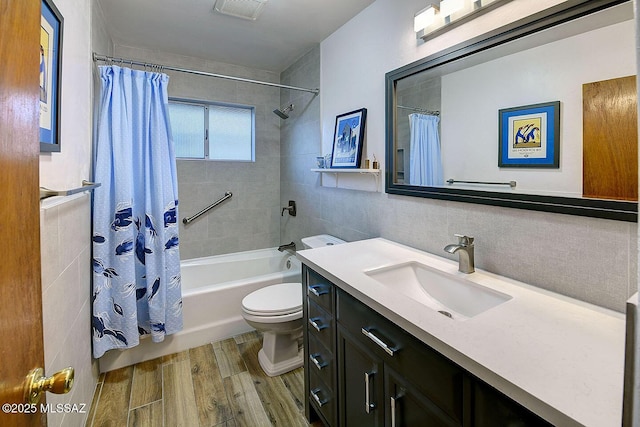 bathroom with tile walls, visible vents, toilet, vanity, and wood finished floors