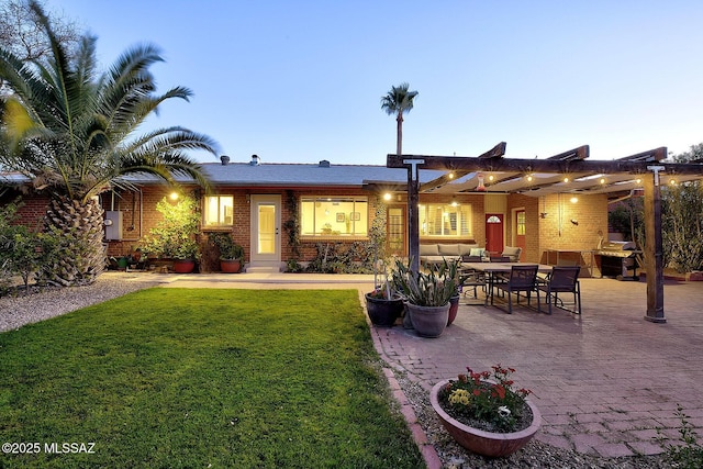 back of house featuring a patio area, brick siding, a yard, and outdoor dining area