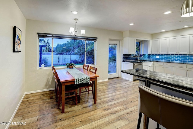 kitchen featuring light wood finished floors, baseboards, white cabinets, and backsplash