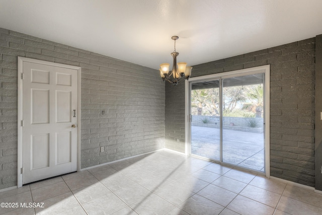 unfurnished dining area featuring light tile patterned flooring, brick wall, and an inviting chandelier