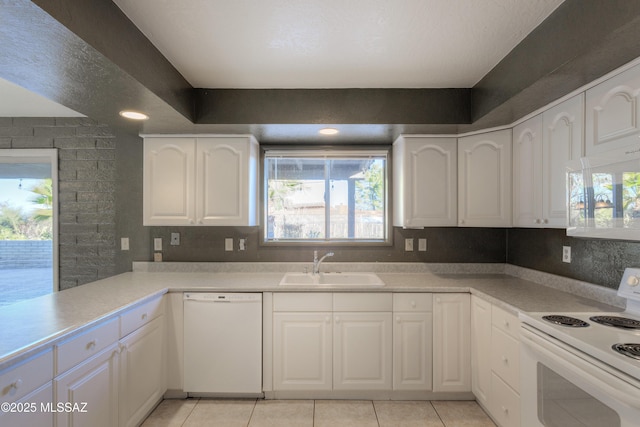 kitchen with sink, white appliances, light tile patterned floors, white cabinetry, and kitchen peninsula