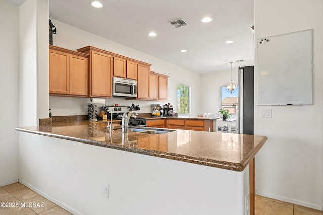 kitchen with pendant lighting, light tile patterned floors, range with gas stovetop, kitchen peninsula, and dark stone counters