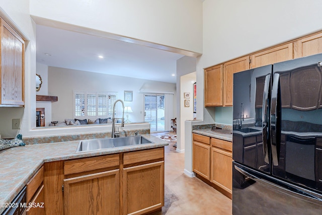 kitchen featuring sink, a towering ceiling, kitchen peninsula, and black fridge