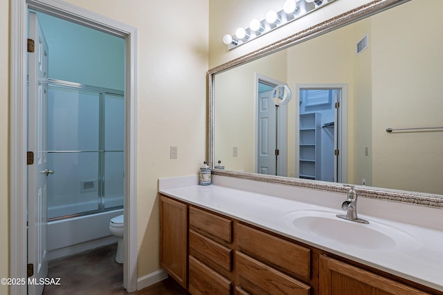 full bathroom with enclosed tub / shower combo, vanity, and toilet