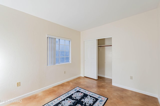 unfurnished bedroom featuring concrete floors and a closet