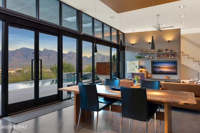 dining area featuring finished concrete floors, a high ceiling, floor to ceiling windows, a mountain view, and recessed lighting