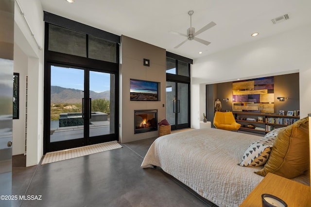 bedroom featuring a mountain view, visible vents, access to exterior, finished concrete flooring, and a glass covered fireplace