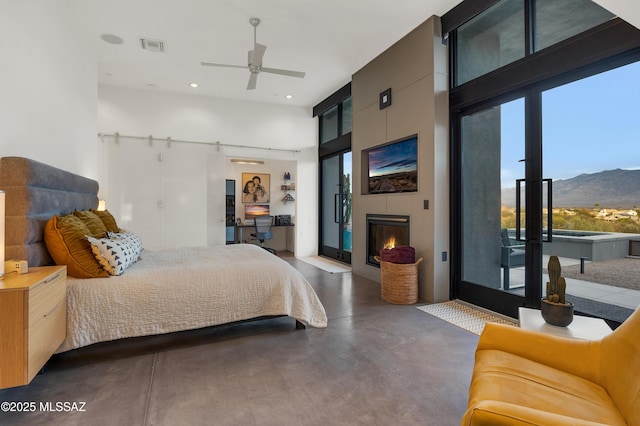 bedroom with finished concrete flooring, access to exterior, a wall of windows, a fireplace, and recessed lighting