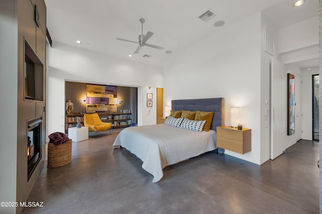 bedroom featuring finished concrete flooring, a lit fireplace, visible vents, and recessed lighting