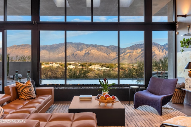 living area with expansive windows, a mountain view, and wood finished floors