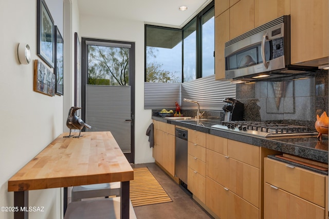 kitchen with stainless steel appliances, butcher block counters, a sink, backsplash, and finished concrete floors