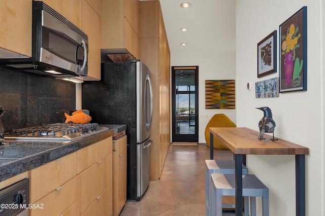 kitchen featuring dark countertops, appliances with stainless steel finishes, finished concrete floors, backsplash, and recessed lighting