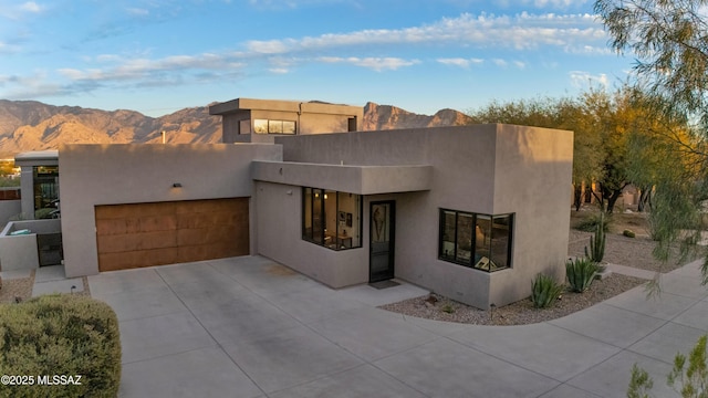 view of front of home featuring a garage, concrete driveway, a mountain view, and stucco siding