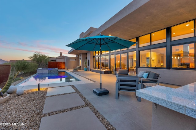 pool at dusk featuring a patio, an outdoor hangout area, fence, an in ground hot tub, and an outdoor pool