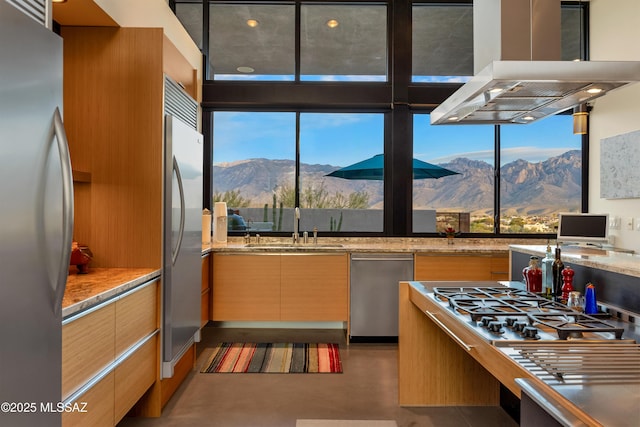 kitchen featuring light stone counters, island range hood, stainless steel appliances, modern cabinets, and finished concrete floors