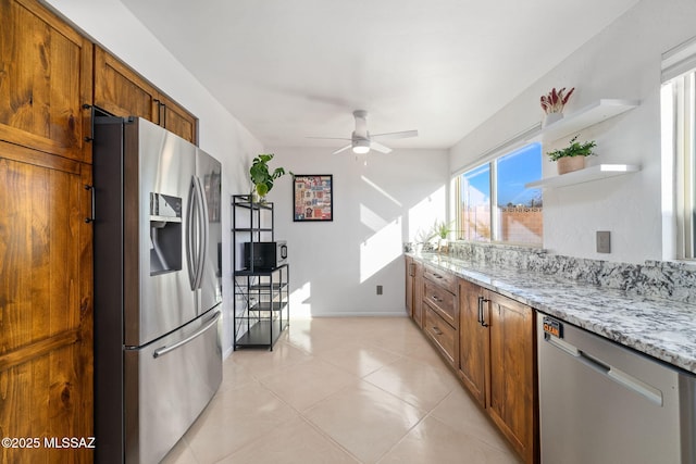 kitchen featuring light stone countertops, appliances with stainless steel finishes, light tile patterned floors, and ceiling fan